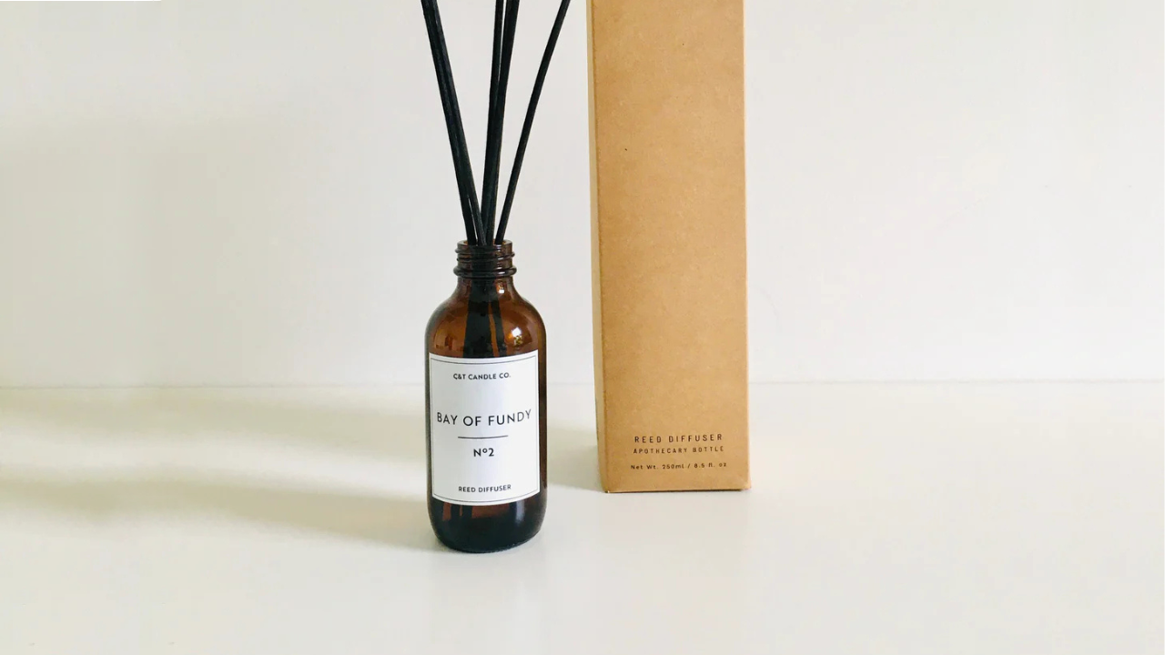 Bay of Fundy Reed Diffuser featuring an amber glass bottle with black rattan reeds and minimalist kraft box packaging. The label reads 'Bay of Fundy No. 2 Reed Diffuser.' A simple and elegant design photographed against a white background.