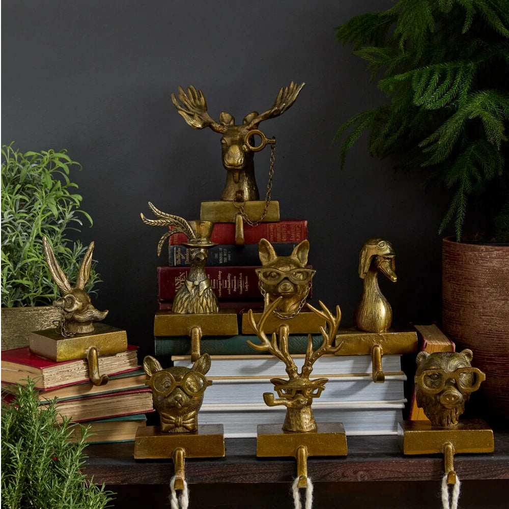 Eloise the Fox stocking holder made from recycled cast aluminum with an antique gold finish. Features a fox head wearing glasses, a weighted base, and a hook for holding stockings.