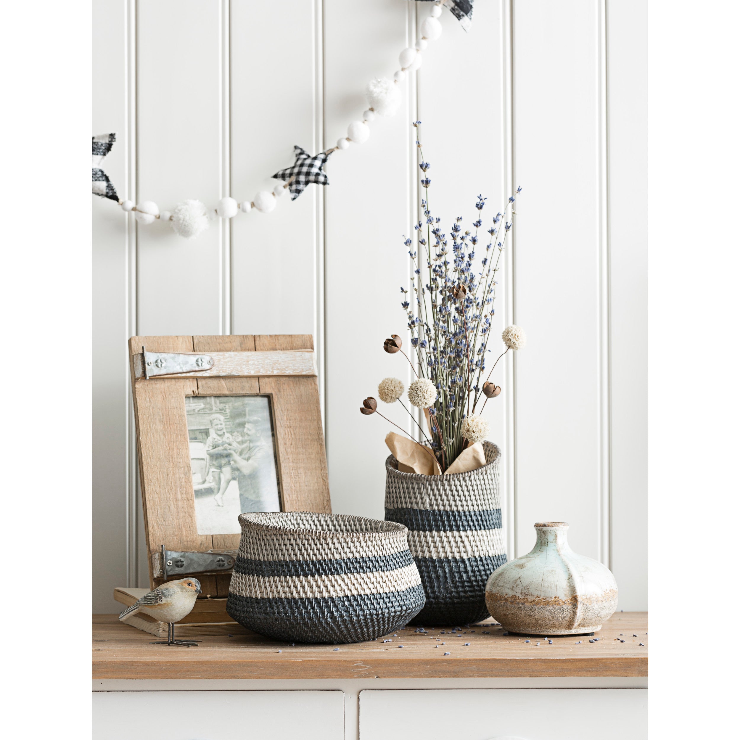 Large distressed ceramic vases on a buffet with baskets filled with dried florals.