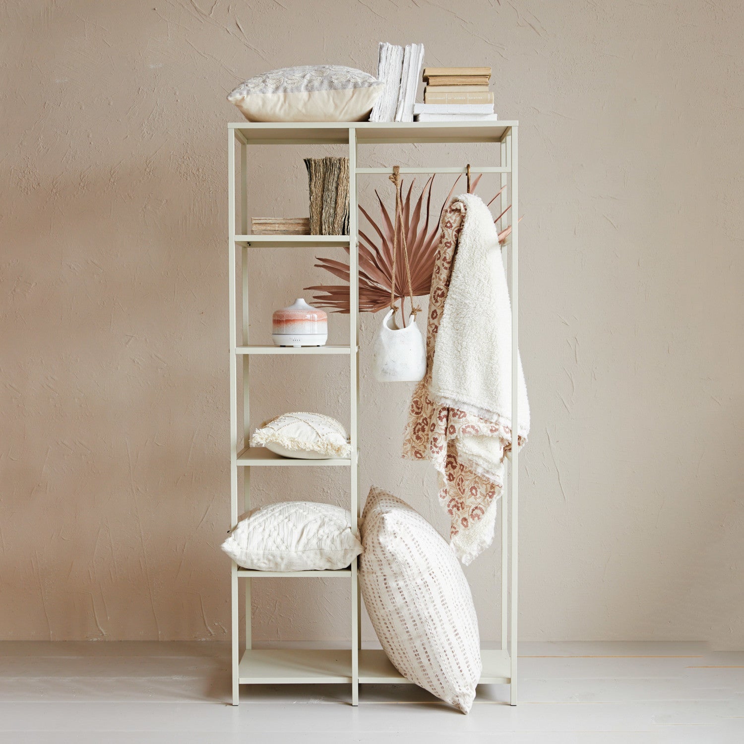 Woven Cotton Printed Throw with Sherpa Back hung from a bedroom storage rack along with cushions, books and a ceramic oil diffuser.  