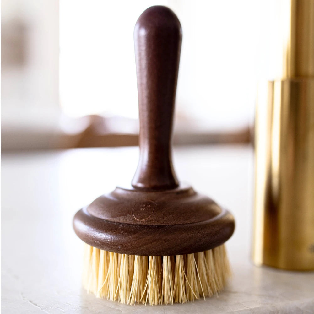 Dish Soap Scrub Brush sitting next to sink on a white marble countertop.