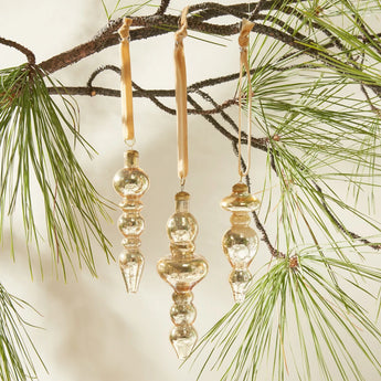 Set of 3 Elegance Ornaments in Gold hung from a pine tree.