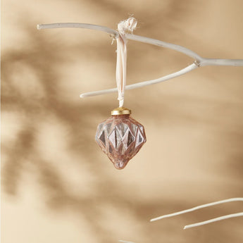 Pale pink jaunty glass ornament with silk ribbon hanging from a white branch.