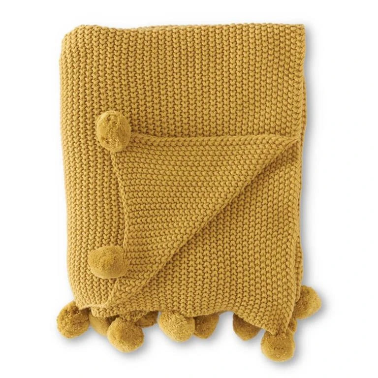 Cotton throw with pom pom details around edges in a deep yellow colour. 