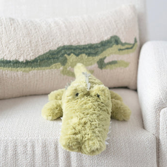 Green plush alligator sitting on couch .