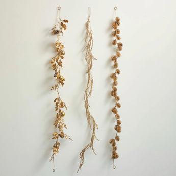 Assortment of three different golden colored faux botanic garlands. 