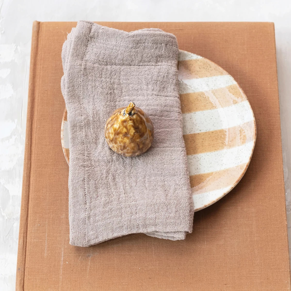 Stoneware Fig with Reactive Glaze placed on a napkin ontop of a plate. 