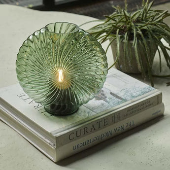 Maeve LED Lamp in the color moss green sitting on top of 2 books.