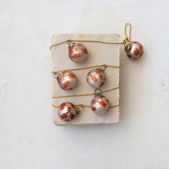 Etched Recycled Mercury Glass Ball Ornament Garland with Gold Cord wrapped around a vintage book. 